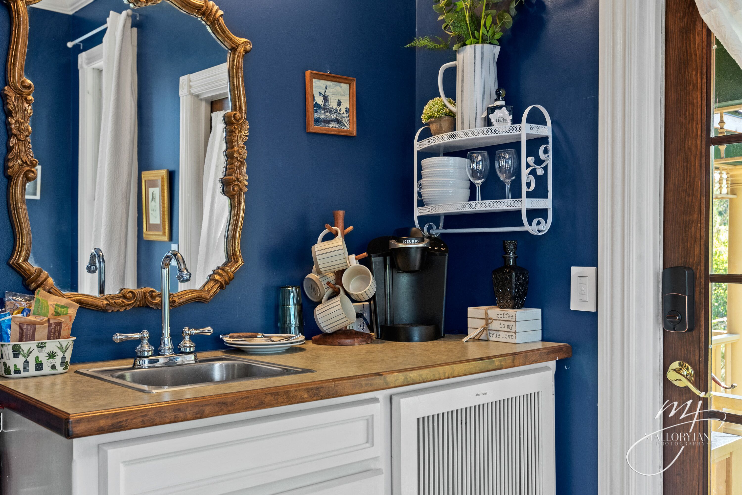 Une salle de bain avec un mur bleu, un meuble-lavabo en bois, un grand miroir et un meuble blanc.