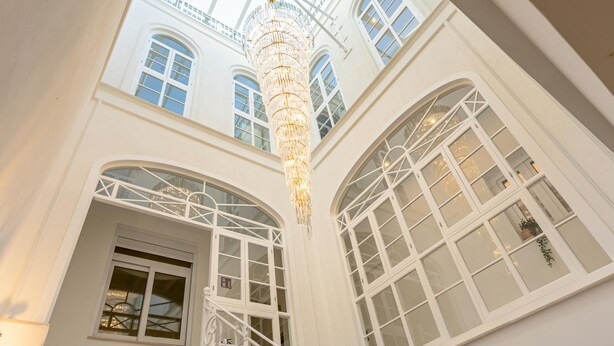 Un intérieur somptueux, avec un plafond haut, de grandes fenêtres en arc de cercle et un lustre imposant.