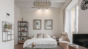 Una camera da letto moderna con un letto, un tavolino in vetro, una televisione, una libreria e un lampadario.