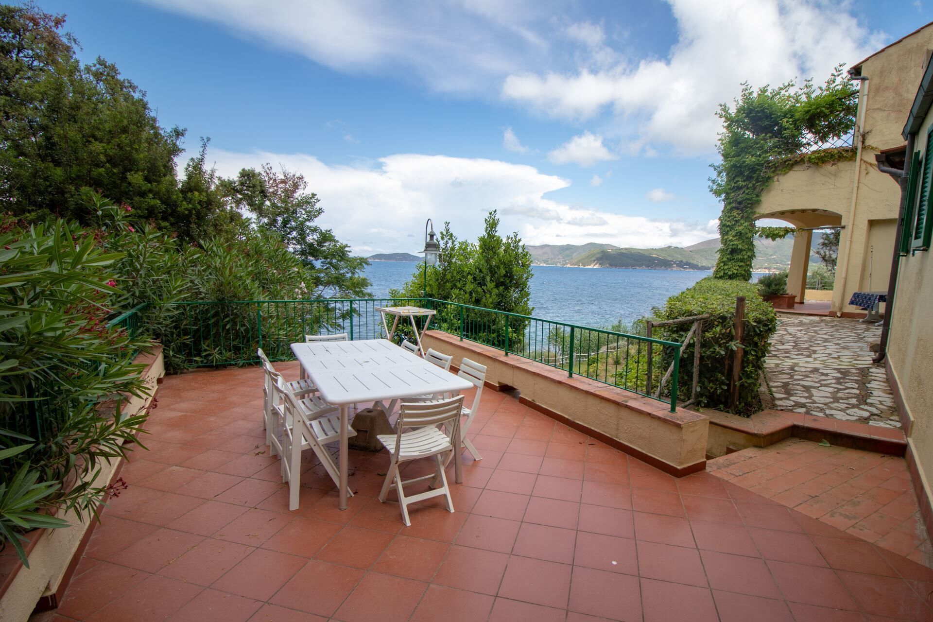 Una terraza con mesa y sillas, con vistas a un cuerpo de agua y colinas.