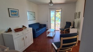 Un salon avec un canapé bleu, un meuble blanc et un coin repas comprenant une table et des chaises.