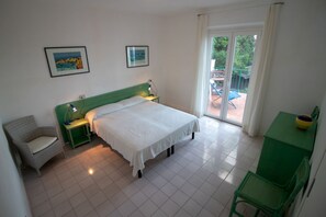 Un dormitorio con cama, una silla, un escritorio y vistas al exterior.