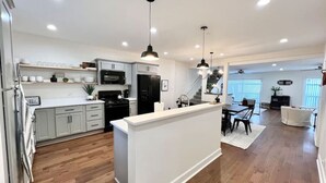 Une cuisine moderne avec des meubles blancs, un îlot central et des luminaires suspendus.