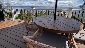 Une terrasse avec une table ronde et des chaises en osier, donnant sur une étendue d’eau.