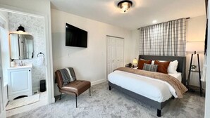 Une chambre à coucher avec un lit, une chaise, une télévision et une porte.