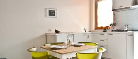 A modern kitchen with white cabinets, a wooden table, and green chairs.