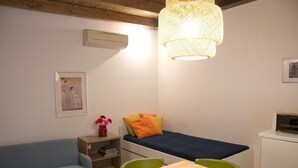 Una habitación pequeña con una cama, un sofá, una mesa y una lámpara colgante.