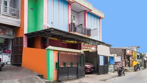 Ein mehrstöckiges Gebäude mit farbenfroher Fassade, einem Balkon und einem verschlossenen Eingang.