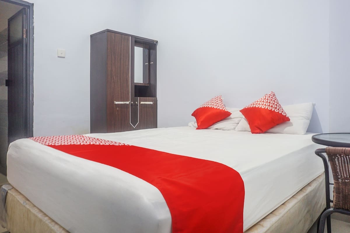 Una habitació d'hotel amb un llit, un armari i una taula petita.