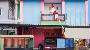 Ein buntes Gebäude mit Balkon, Flagge und einem parkenden Auto.