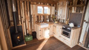 A rustic kitchen with wooden cabinetry, a stove, a sink, and a window. - The Sandpiper - sleeps 4 guests  in 2 bedrooms (Beadnell)