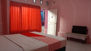 A bedroom with a bed, a television on a stand, and a door leading to another room. - OYO 90555 Vina Pavilion (Bengkulu)