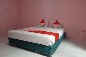 Un lit recouvert d’une couvre-lit blanche et rouge, agrémenté de deux oreillers rouges et d’une jupe de lit turquoise, dans une pièce aux murs roses et au sol carrelé de blanc.