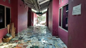 A corridor with a tiled floor, pink walls, and a sign indicating a park with a view of the sea. - OYO 90555 Vina Pavilion (Bengkulu)