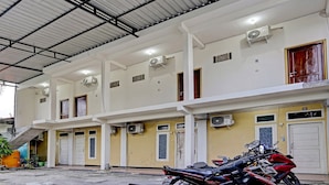 A multi-story building with air conditioning units, a covered parking area, and several motorcycles parked in front. - Hotel O Grand Syariah Hagawa Lamongan Near SPORT CENTER LAMONGAN (Lamongan)