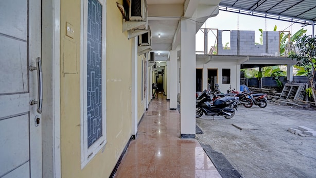 A corridor with a tiled floor leading to a covered parking area with motorcycles. - Hotel O Grand Syariah Hagawa Lamongan Near SPORT CENTER LAMONGAN (Lamongan)