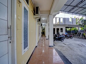 A corridor with a tiled floor leading to a covered parking area with motorcycles. - Hotel O Grand Syariah Hagawa Lamongan Near SPORT CENTER LAMONGAN (Lamongan)