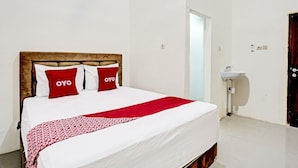 A neatly made bed with white and red bedding, a wooden headboard, and a red throw blanket. - Hotel O Grand Syariah Hagawa Lamongan Near SPORT CENTER LAMONGAN (Lamongan)