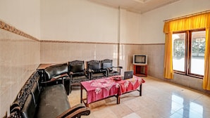 A room with a sofa, chairs, a table with a laptop, a TV, and a window with curtains. - SPOT ON 91715 Hotel Citra Dewi 1 (Bandungan)