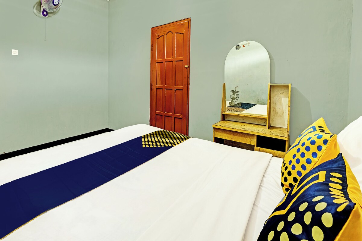 Un dormitorio con una cama, un aparador de madera, un espejo y una puerta.