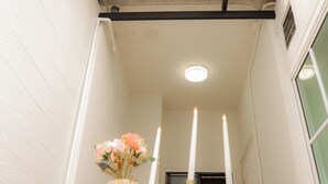 A narrow hallway with a white door, a small table with a bottle and glasses, and a vase with flowers. - HaneulHotelChiamai (Chiang Mai)