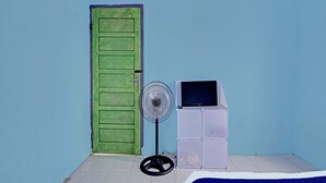 A room with a green door, a standing fan, and a white cabinet. - SPOT ON 91918 Najla Guest House Syariah (Pekanbaru)