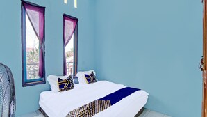 A bedroom with a bed, two windows with curtains, a fan, and a door. - SPOT ON 91918 Najla Guest House Syariah (Pekanbaru)
