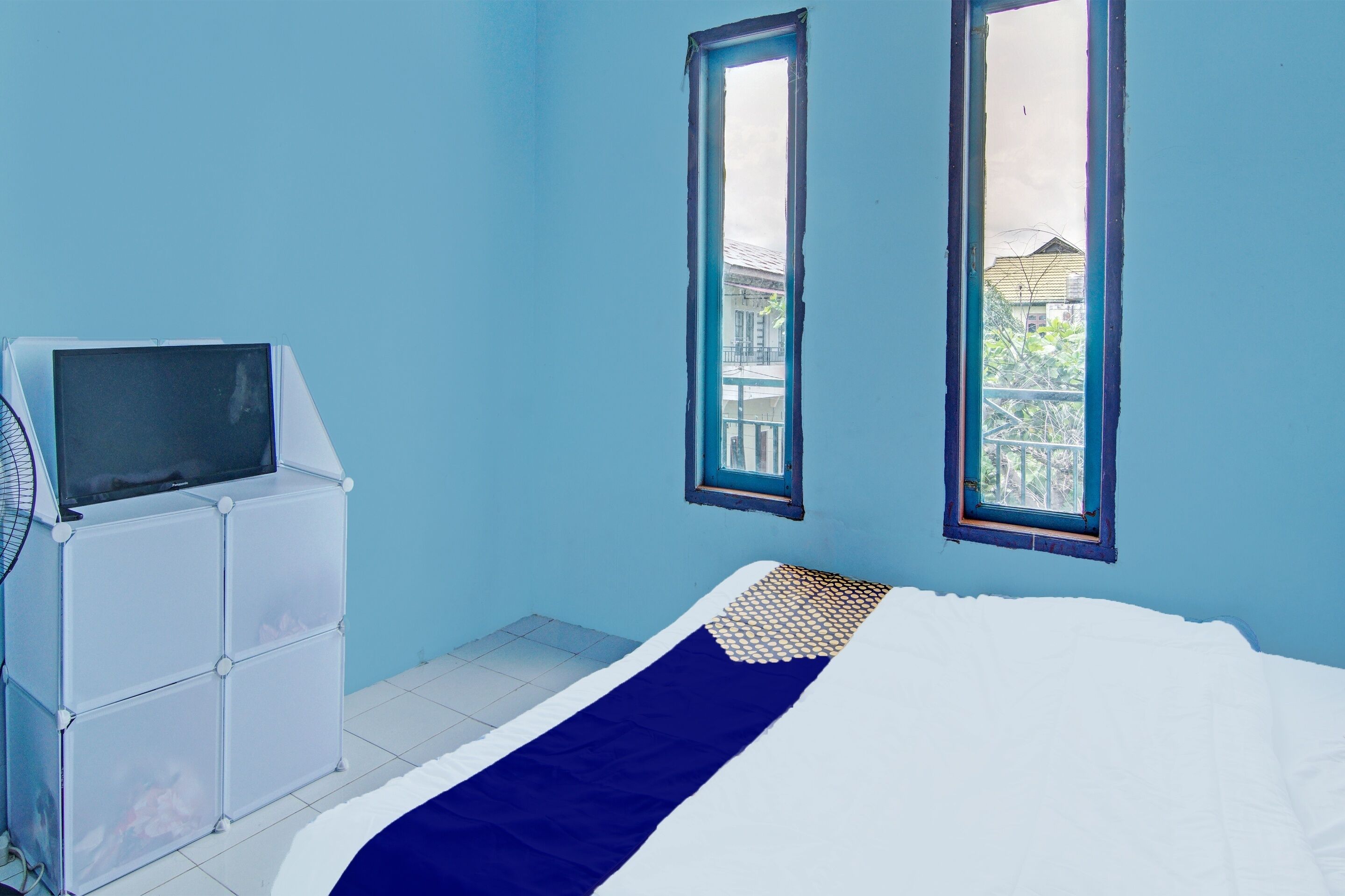 Quarto com cama, televisão e janela.