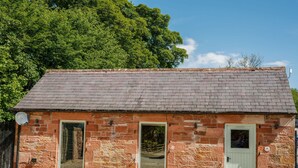 A stone building with a sloped roof, two doors, and a small window. - A cottage that sleeps 2 guests  in 1 bedroom (Longtown)