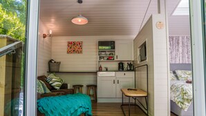 Una habitación acogedora con cama, una kitchenette pequeña, una mesa de comedor y ventana con vistas a zonas verdes.