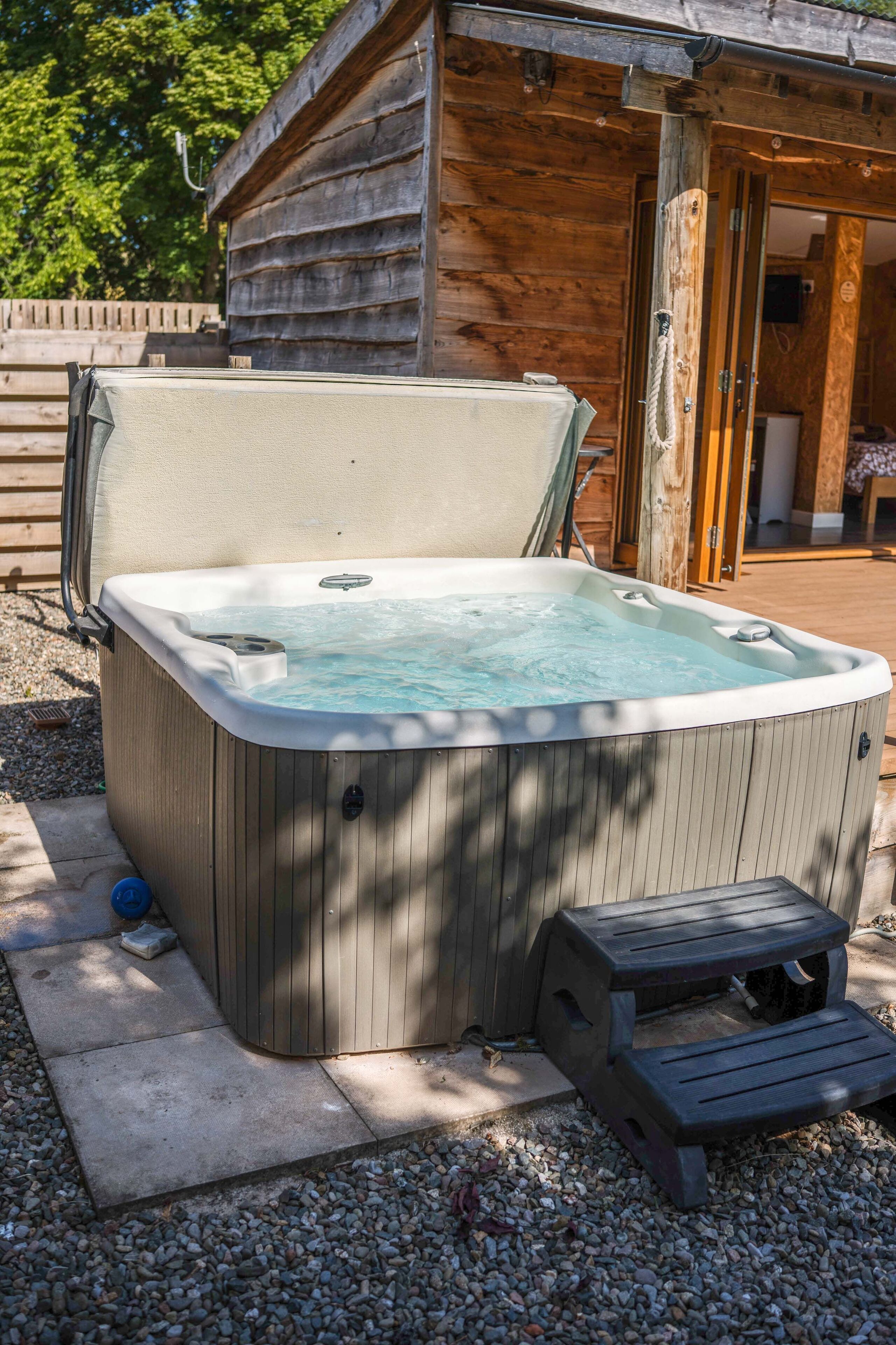 Un jacuzzi con una terraza de madera y un edificio de madera al fondo.