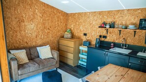 Ein gemütlicher Wohnraum mit Küchenzeile, einer Couch, einem Holztisch und einem kleinen Teppich.