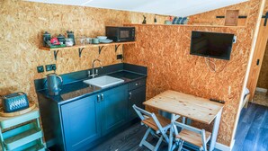 Eine kompakte Küche mit Spüle, Mikrowelle und Holztisch mit Stühlen.