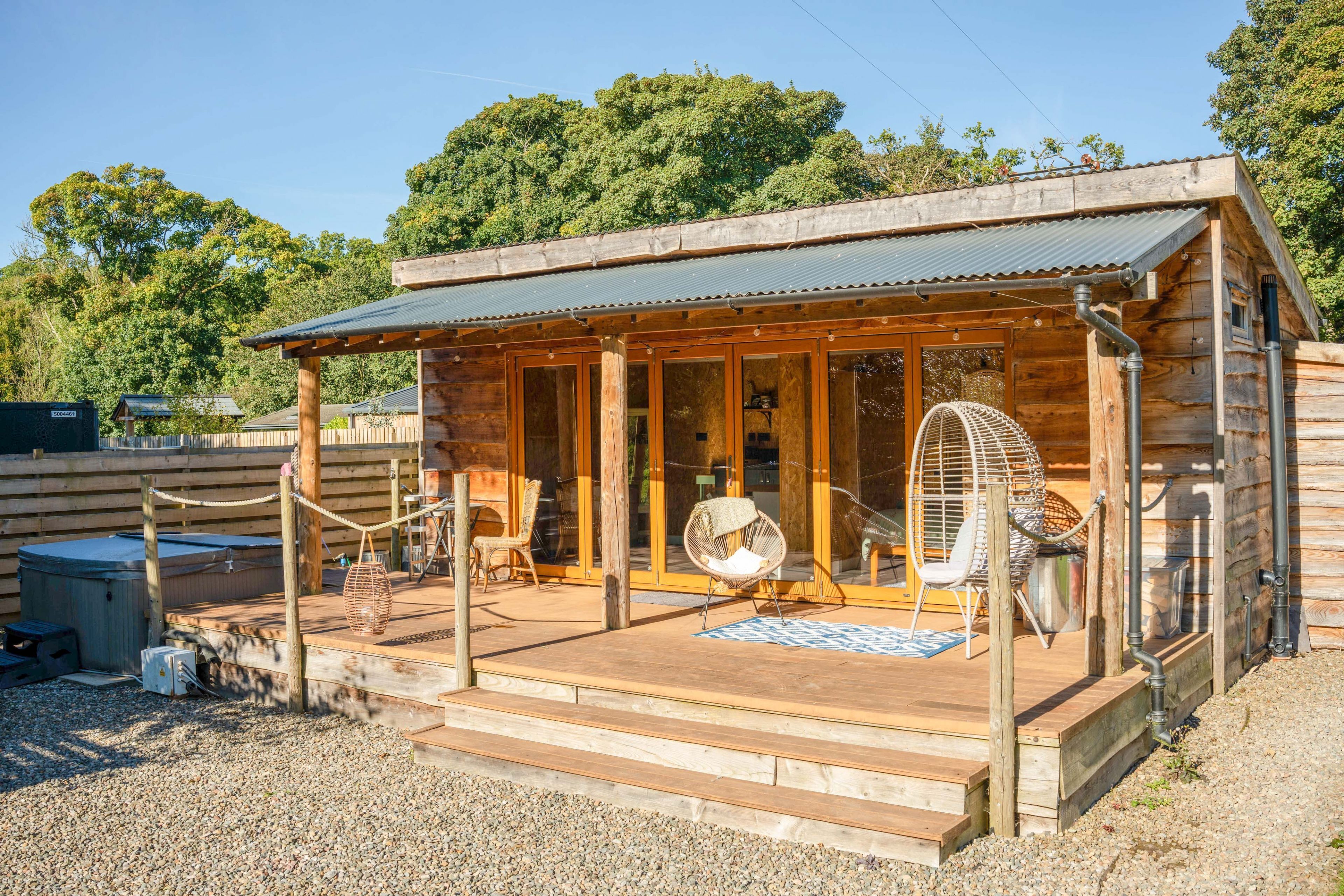 Eine Holzhütte mit Veranda, Whirlpool und Ventilator.