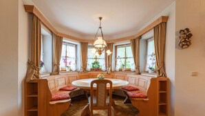 A cozy dining area with a round table, wooden bench seating, and large windows with curtains.