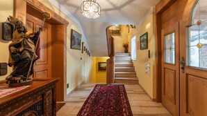A wooden staircase with a red patterned carpet leading to a second floor.