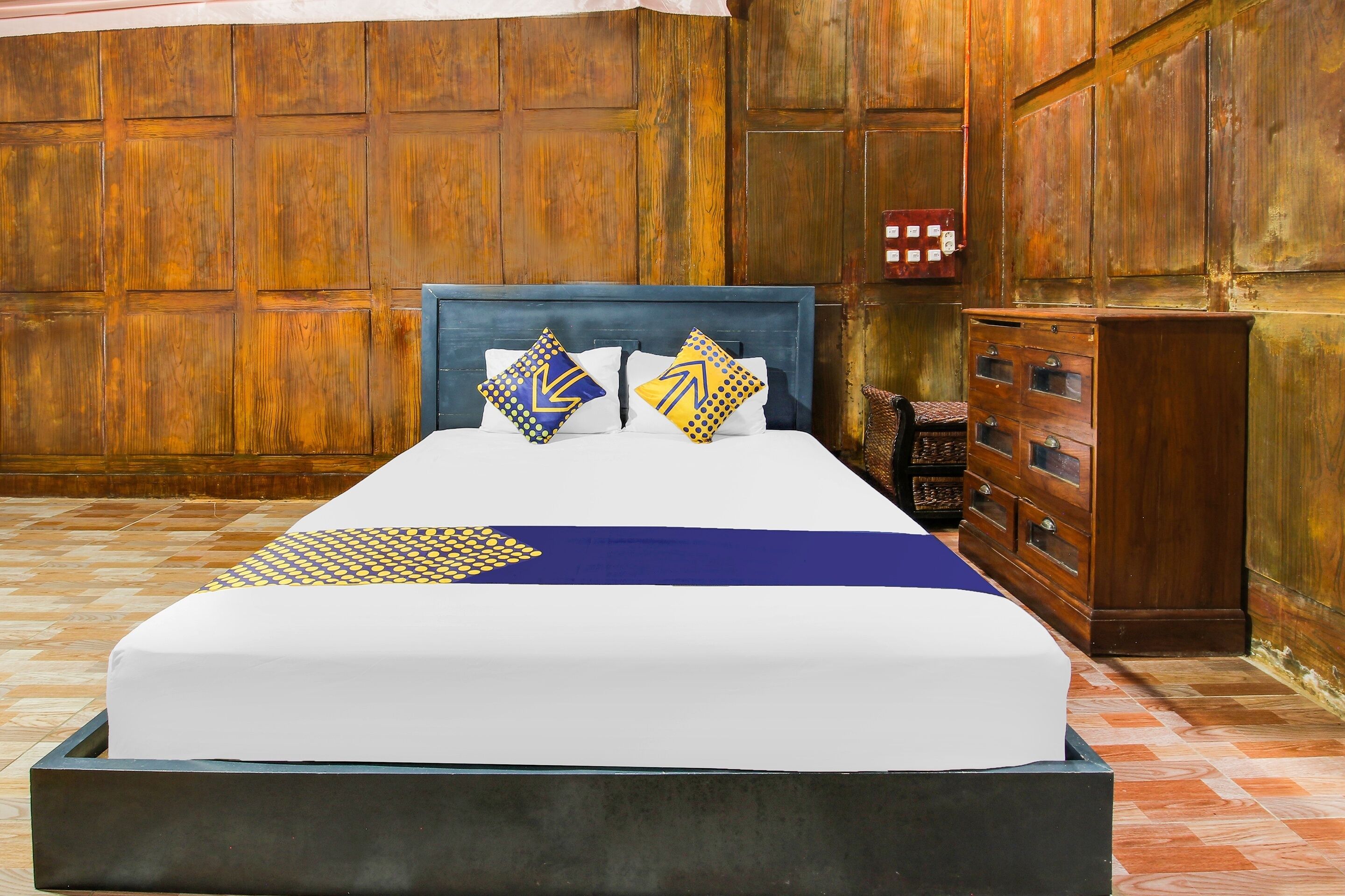 A bed with a blue headboard, two pillows with geometric patterns, and a blue blanket.