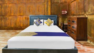A bed with a blue headboard, two pillows with geometric patterns, and a blue blanket.
