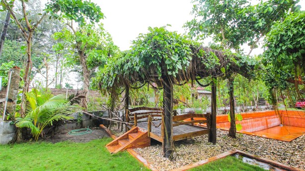 A garden with a wooden swing set, a small pond, and various plants. - OYO 92083 Lailik Gilang Guesthouse (Werinama)