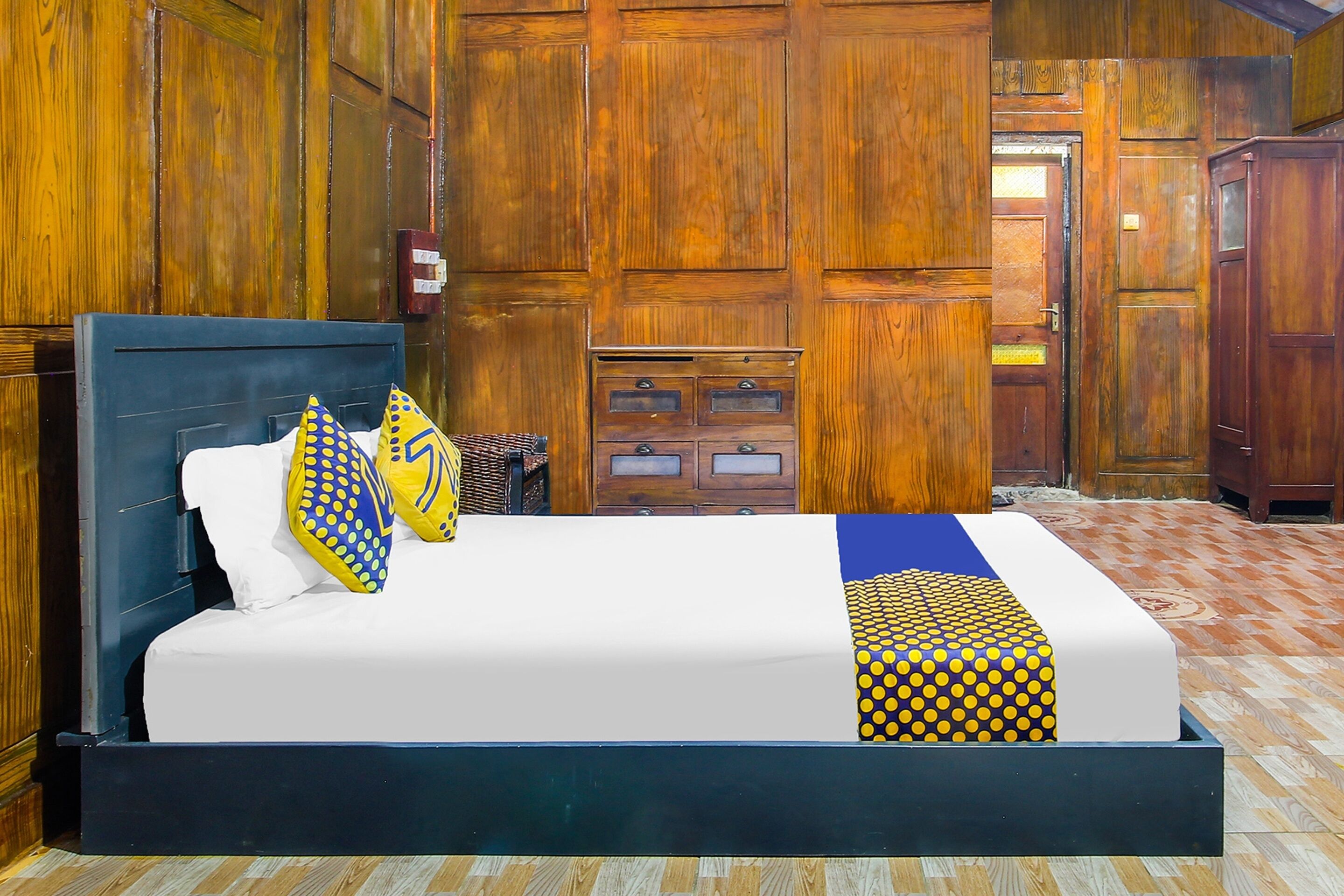 Un letto con materasso bianco, testiera blu e copripiumino decorato.