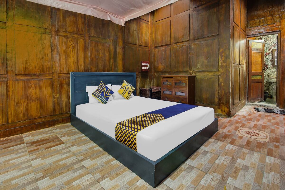 Una cama grande con cabecera de madera, un armario de madera y un suelo estampado.