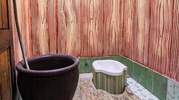 A bathroom with a large wooden bath tub, a toilet, and a shower area.