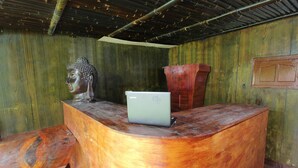 A wooden reception desk with a laptop, a Buddha statue, and a red vase. - OYO 92083 Lailik Gilang Guesthouse (Werinama)