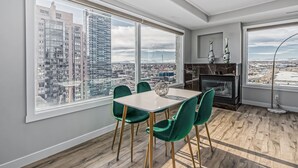 Een moderne keuken met een groot raam, een zithoek met groene stoelen en uitzicht op een stadsgezicht.