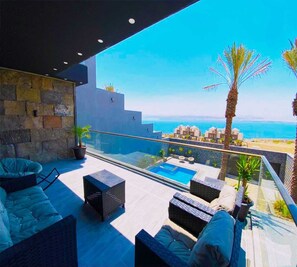 Une terrasse sur le toit avec une piscine, des espaces de détente en plein air et une vue sur la mer.