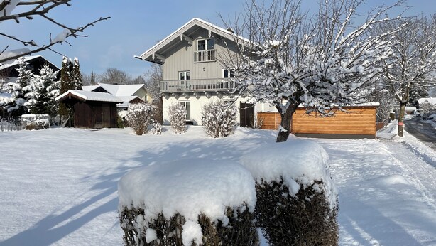 Een woonwijk met een huis met een balkon en een sneeuwbedekte tuin.