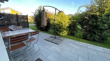 Eine Außenpatio-Terrasse mit Tisch und Stühlen, eine Pergola mit Dach und Blick auf eine grüne Landschaft.