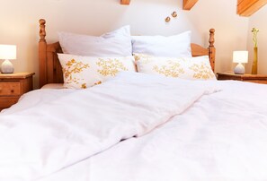 A neatly made bed with white bedding and two decorative pillows with yellow floral patterns.