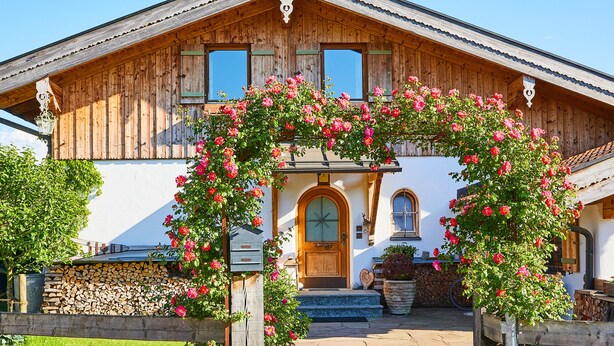 Een houten huis met een grote bloemstuk in de entree.