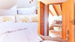 Een slaapkamer met een bed, witte beddengoed en een houten garderobe.